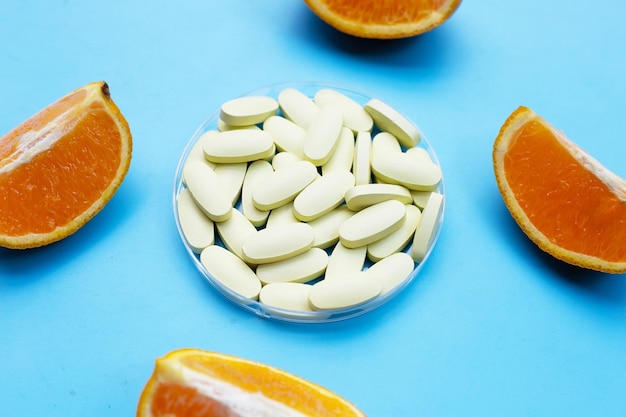 Vitamin c pills with orange fruit on blue background