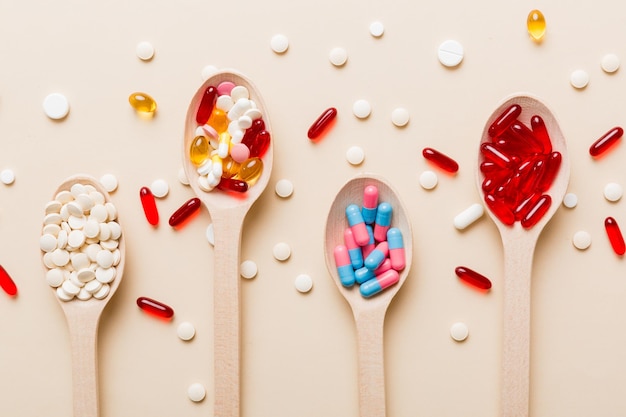 Vitamin capsules in a spoon on a colored background Pills served as a healthy meal Red soft gel vitamin supplement capsules on spoon