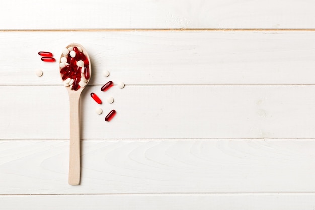 Vitamin capsules in a wooden spoon on a colored background Pills served as a healthy meal Drugs pharmacy medicine or medical healthycare concept