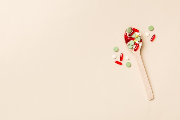 Vitamin capsules in a wooden spoon on a colored background Pills served as a healthy meal Drugs pharmacy medicine or medical healthycare concept