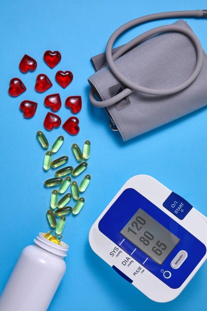 Vitamin D and red decorative hearts and cardiac tonometer on a blue background Prevention and treatment of atherosclerosis hypertension and ischemic disease