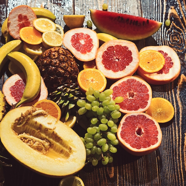 Vitamin food and health eating watermelon and melon with banana orange pineapple lemon with grapefruit and grapes layout Fresh fruits on wooden table Tropical and exotic fruits Detox diet concept