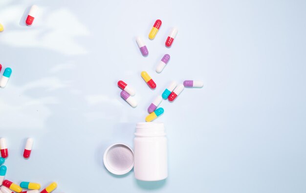 Vitamin pills flat lay on a blue background in a plastic white bottle. Vitamin medical prescription.