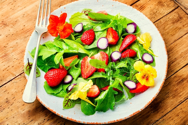 Vitamin salad with strawberries,spinach,nasturtium and arugula.Low calorie salad on rustic wooden table