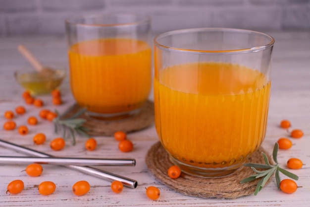 Vitamin sea buckthorn juice in glasses on a white wooden background.