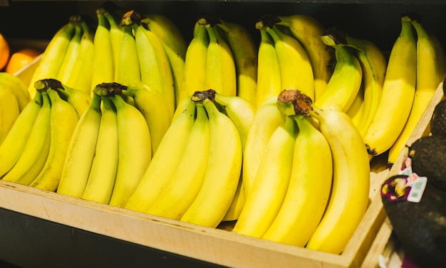 Vitaminized exotic fruit Young modern woman in casual clothes chooses products in the store of organic goods and puts the bananas in the basket