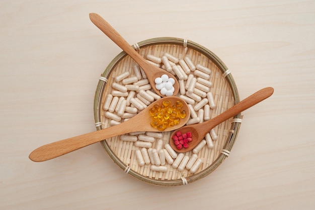 Vitamins minerals and nutritional supplements in wooden spoons inside a braided bamboo plate