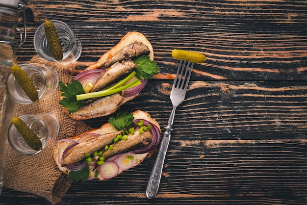 Vodka and a set of sandwiches with sprats and caviar onion and parsley on a wooden background Top view Copy space