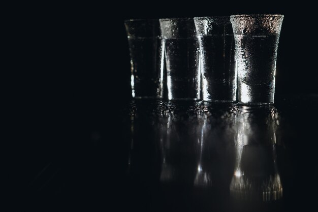 Vodka in shot glasses on dark background.