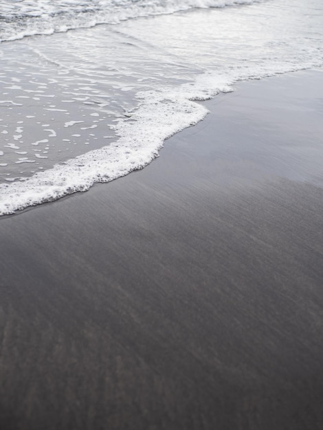 Volcanic dark sand beach shore wave