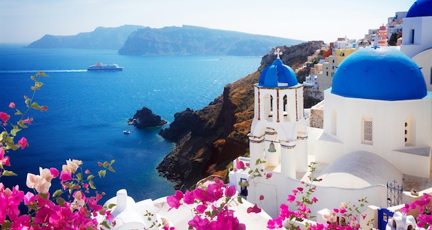 volcano caldera with blue church domes Oia with flowers Santorini toned