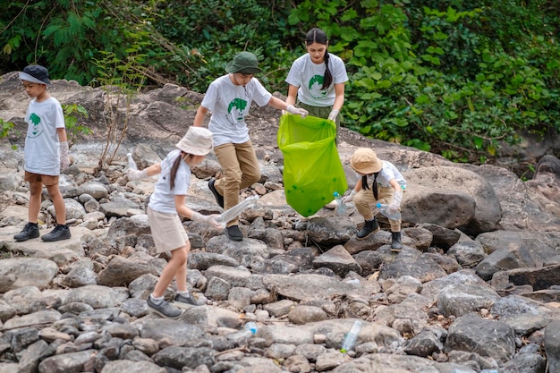 Volunteer Asian and children are collecting plastic bottles that flow through the stream into garbag