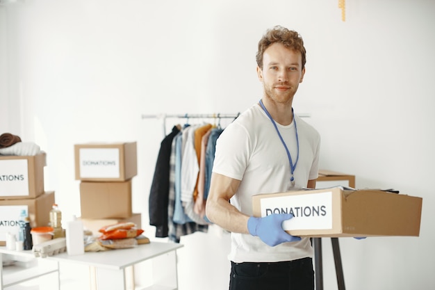 Volunteer collects things from donations. Guy packs boxes with things. Man compares endowment.