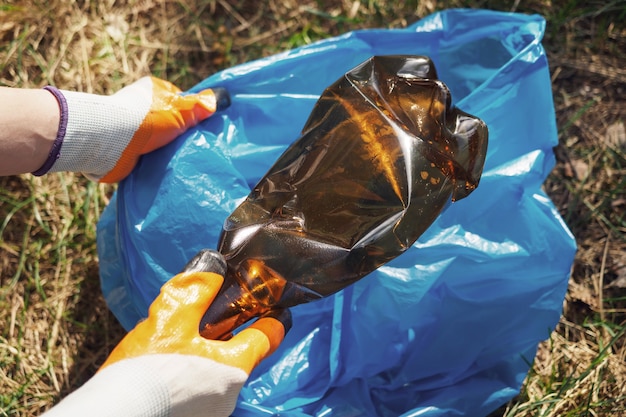 Photo a volunteer and eco activist collects garbage in bags, in the forest, close-up. recycling of plastic waste, environmental protection. protecting the planet from debris. ecology concept.