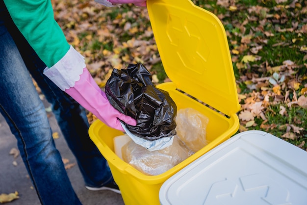 Volunteer girl sorts garbage in the street of the park. Concept of recycling.