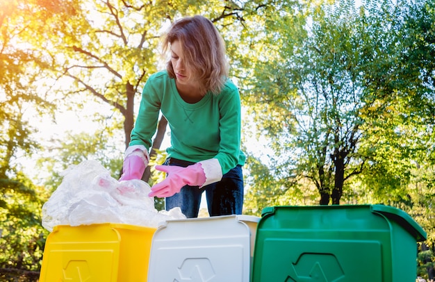 Volunteer girl sorts garbage in the street of the park. Concept of recycling.