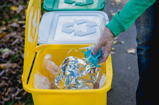 Volunteer girl sorts garbage in the street of the park. Concept of recycling.