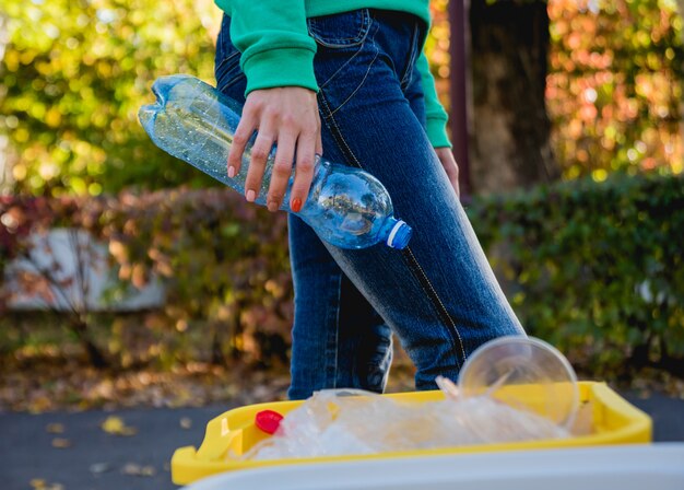 Volunteer girl sorts garbage in the street of the park. Concept of recycling.