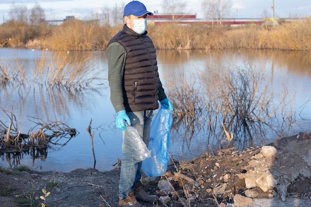 A volunteer in a protective face mask collects garbage Ecology and the environment