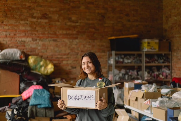 Volunteer teengirl preparing donation boxes for people Donation clothing for refugees support of war victims Humanitarian aid conceptHelping people