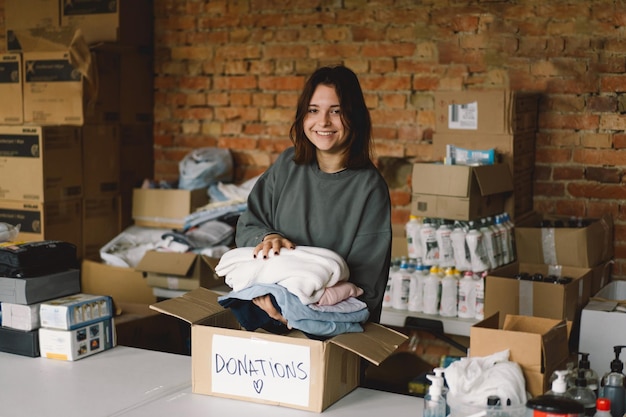 Volunteer teengirl preparing donation boxes for people Donation clothing for refugees support of war victims Humanitarian aid conceptHelping people