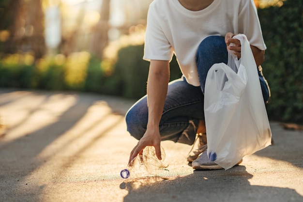 Volunteer woman collects trash in the trash bag