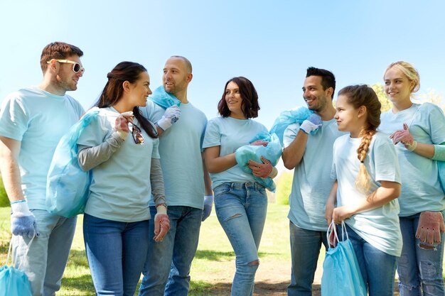 Photo volunteering charity people and ecology concept group of happy volunteers with garbage bags talking in park