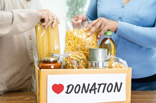 Photo volunteers putting various dry food in donation box for help people