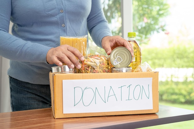 Photo volunteers putting various dry food in donation box for help people