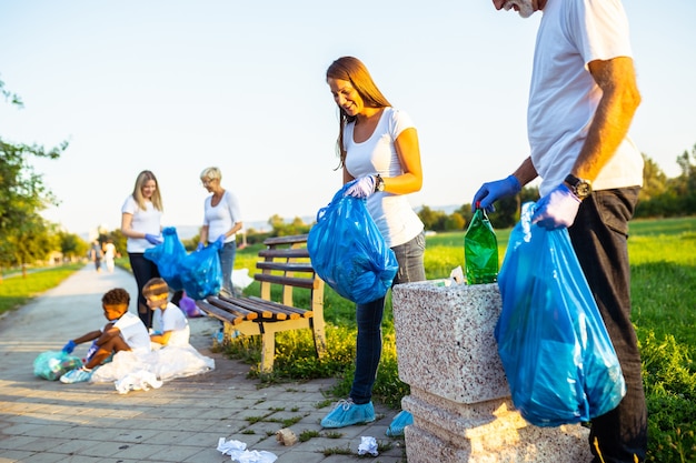 Volunteers with garbage bags cleaning up garbage outdoors - ecology concept.