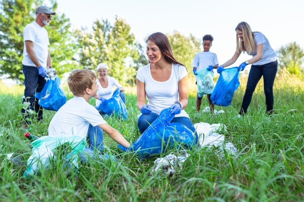 Volunteers with garbage bags cleaning up garbage outdoors - ecology concept.