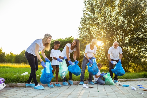 Volunteers with garbage bags cleaning up garbage outdoors - ecology concept.