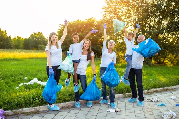 Volunteers with garbage bags cleaning up garbage outdoors - ecology concept.