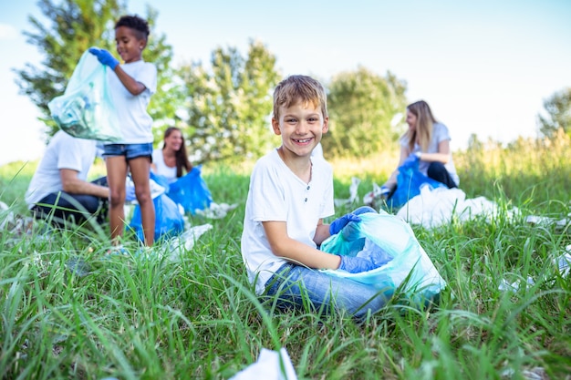 Volunteers with garbage bags cleaning up garbage outdoors - ecology concept.