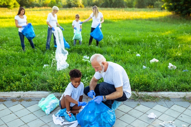 Volunteers with garbage bags cleaning up garbage outdoors - ecology concept.