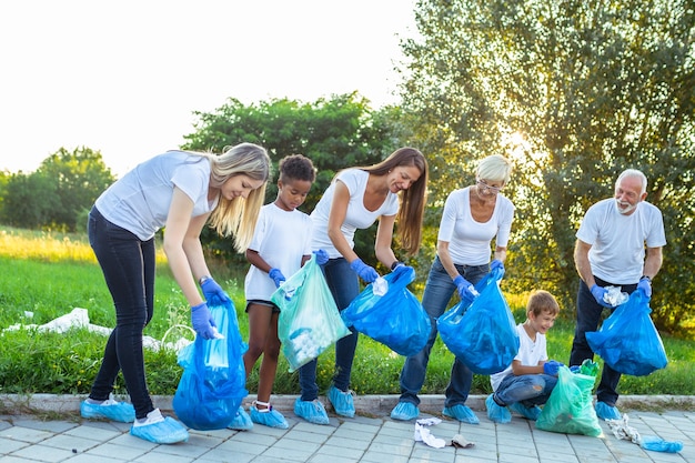 Volunteers with garbage bags cleaning up garbage outdoors - ecology concept.