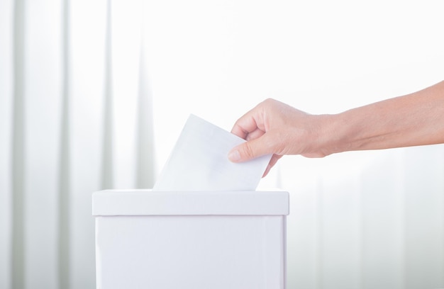 Voting on election day Caucasian white woman hand putting blank ballot in box