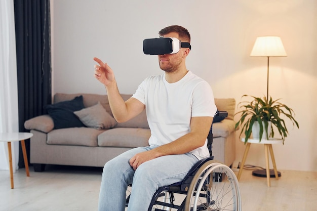 In VR glasses Disabled man in wheelchair is at home