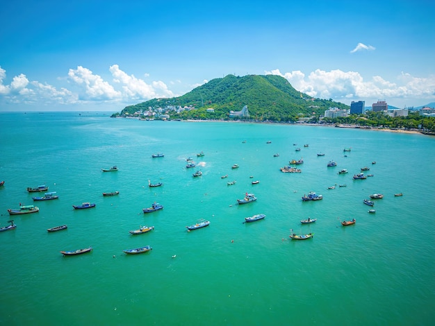 Vung Tau city aerial view with beautiful sunset and so many boats Panoramic coastal Vung Tau view from above with waves coastline streets coconut trees and Tao Phung mountain in Vietnam