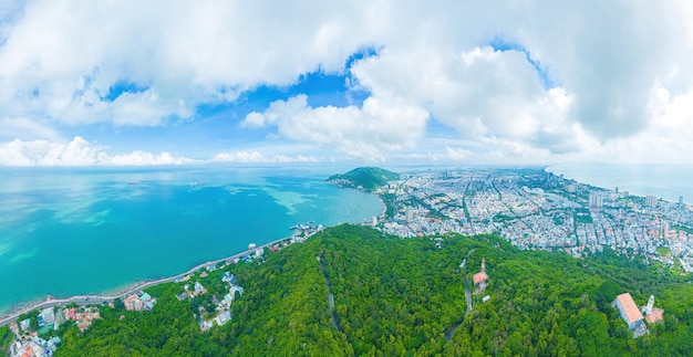 Vung Tau city aerial view with beautiful sunset and so many boats Panoramic coastal Vung Tau view from above with waves coastline streets coconut trees and Tao Phung mountain in Vietnam