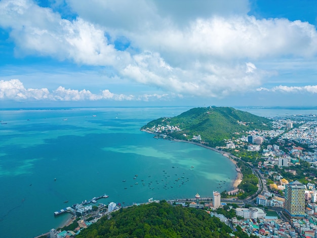 Vung Tau city aerial view with beautiful sunset and so many boats Panoramic coastal Vung Tau view from above with waves coastline streets coconut trees and Tao Phung mountain in Vietnam