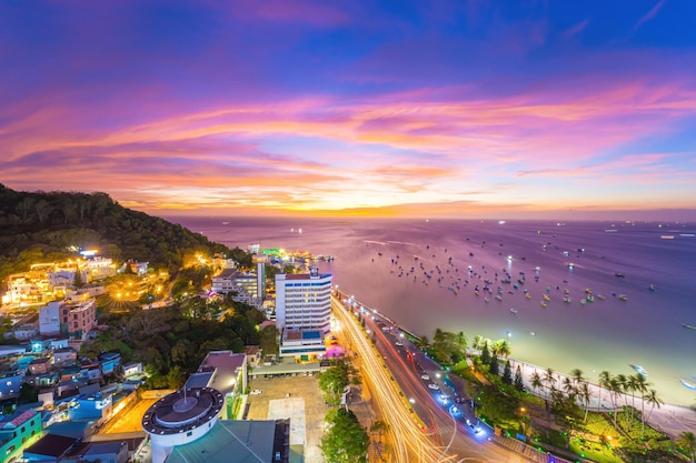 Vung Tau city aerial view with beautiful sunset and so many boats Panoramic coastal Vung Tau view from above with waves coastline streets coconut trees and Tao Phung mountain in Vietnam