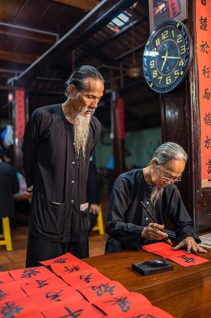 Vung Tau Vietnam JAN 12 2023 Vietnamese scholar writes calligraphy at Long Son Calligraphy festival is a popular tradition during Tet holiday Writing couplets for Spring Festival new year