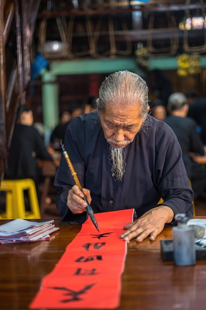 Vung Tau Vietnam JAN 12 2023 Vietnamese scholar writes calligraphy at Long Son Calligraphy festival is a popular tradition during Tet holiday Writing couplets for Spring Festival new year