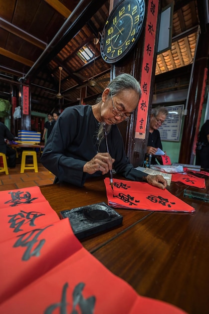 Vung Tau Vietnam JAN 12 2023 Vietnamese scholar writes calligraphy at Long Son Calligraphy festival is a popular tradition during Tet holiday Writing couplets for Spring Festival new year