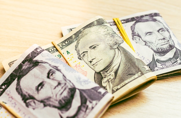 wads of folded US Dollar bills on a wooden table in closeup photography