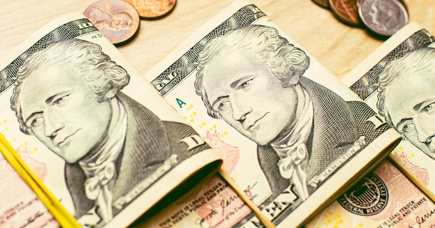 wads of folded US Dollar bills on a wooden table in closeup photography