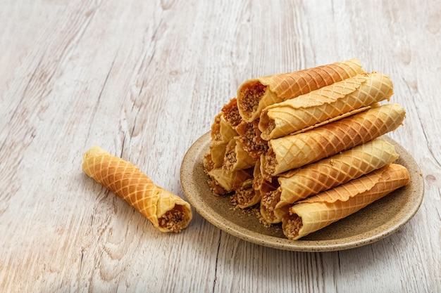 Wafer rolls with cream on a plate. Homemade baking. Wooden background. Photo