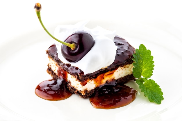 Waffle cake with cherry and whipped cream with mint leaf on white plate