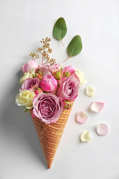 Waffle cone with composition of flowers and branches on white background